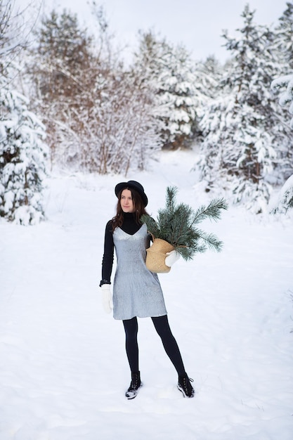 A young girl in a silvery dress and hat stands with her back in the middle of a beautiful winter forest