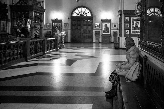 Photo a young girl sits on a bench in an orthodox church and prays black and white photography