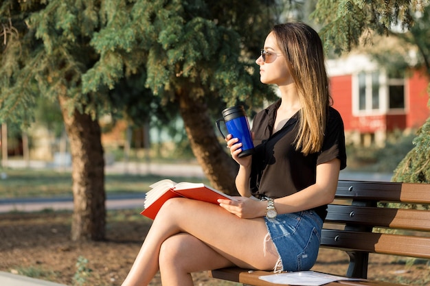 A young girl sits on a bench in a park and makes notes Dressed in a free style Business woman talking on the phone with customers