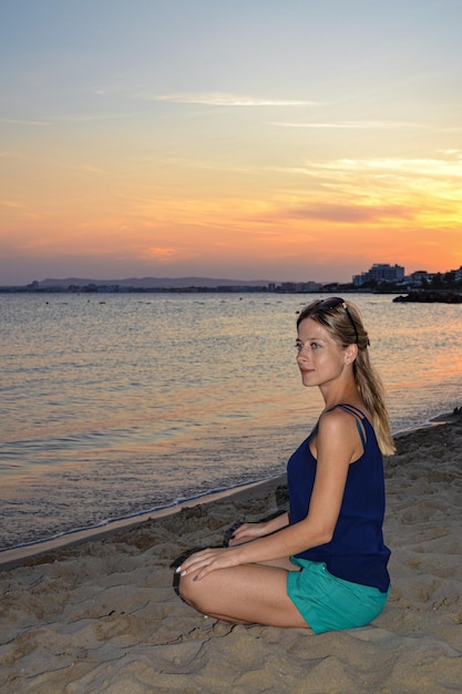 A young girl sits on the seashore at sunset life style freedom and relaxation