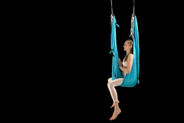 Young girl sits in sports hammock and meditates Fly yoga in hammocks Antigravity yoga Copy space