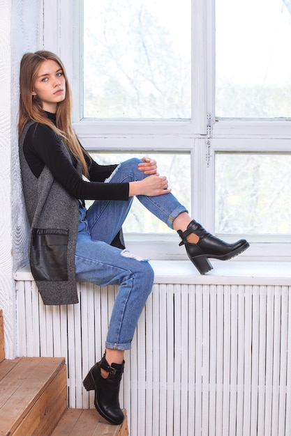 A young girl sits on the windowsill. In the Studio.