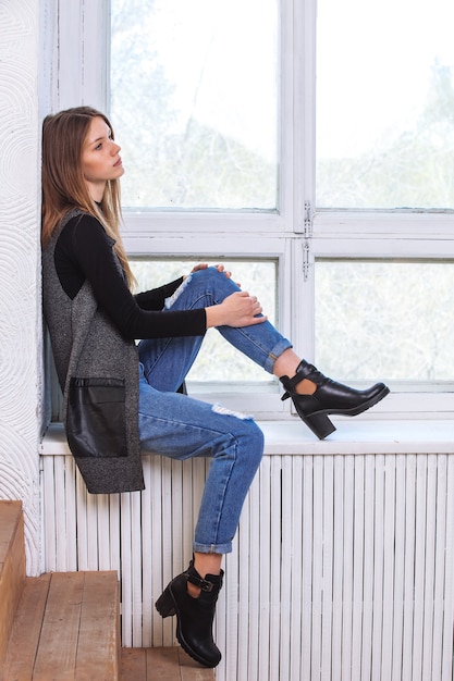 A young girl sits on the windowsill. In the Studio.