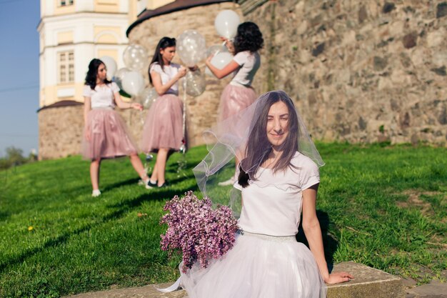 The young girl sits with a beautiful bouquet and her face is covered with veil