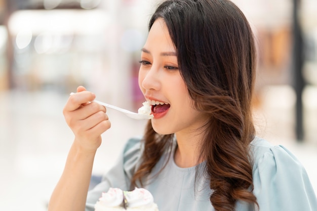 Young girl sitting alone eating cream cake at the mall