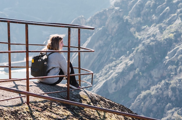 Young girl sitting on a mountain cliff