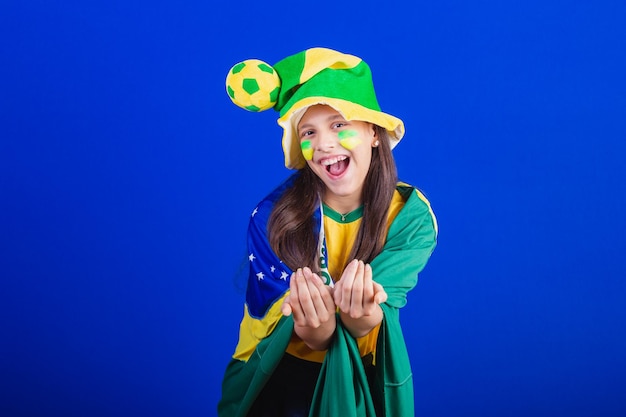 Young girl soccer fan from Brazil dressed in hat and flag calling with your hands