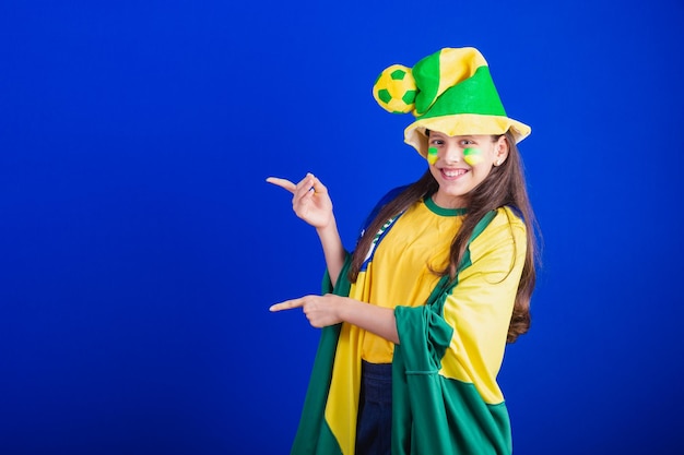 Young girl soccer fan from Brazil dressed in hat and flag pointing at something