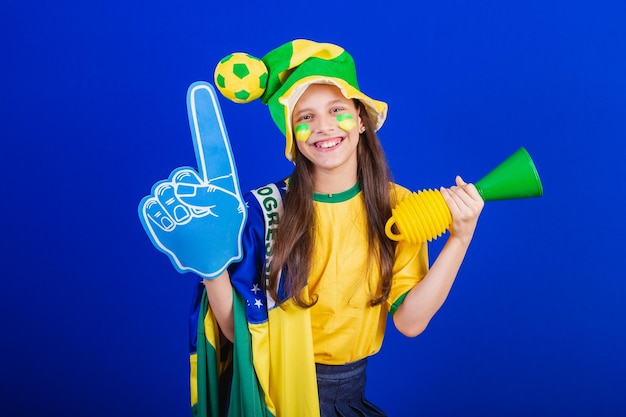 Young girl soccer fan from Brazil dressed in hat and flag using foam finger