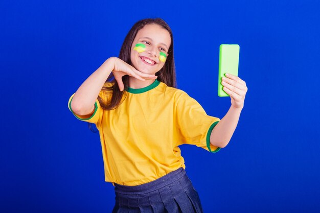 Young girl soccer fan from Brazil holding cellphone selfie self portrait Smartphone applications