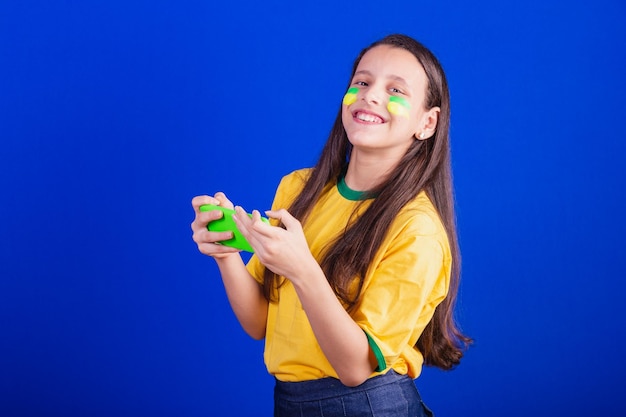 Young girl soccer fan from Brazil holding cellphone watching game cheering for Smartphone applications