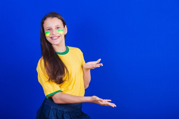 Young girl soccer fan from Brazil presenting something with their hands