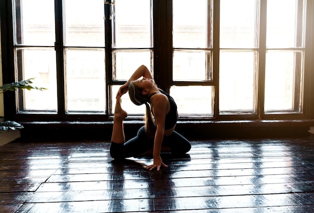 A young girl in sportswear does yoga fitness at home sports at home stretching