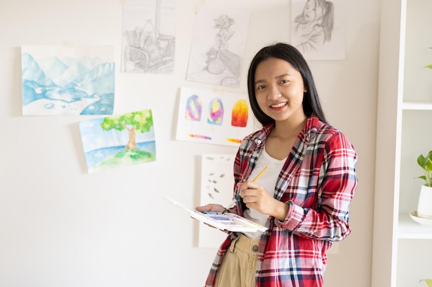 Young girl standing on the floor and hold Color palette and brush at room Hobby and art study at home