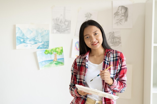 Young girl standing on the floor and hold Color palette and brush at room Hobby and art study at home