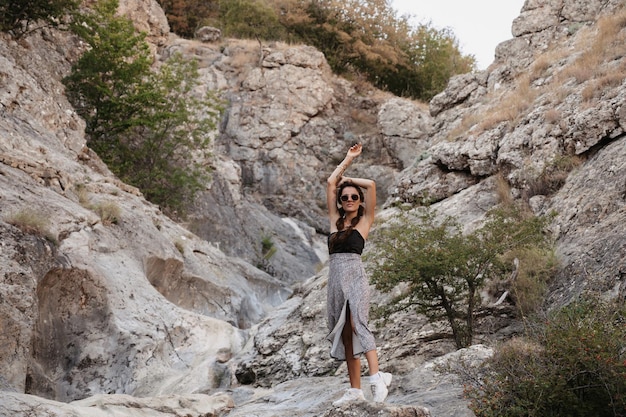 A young girl standing in a rocky valley in a hilly area Hiking in the hills Active recreation