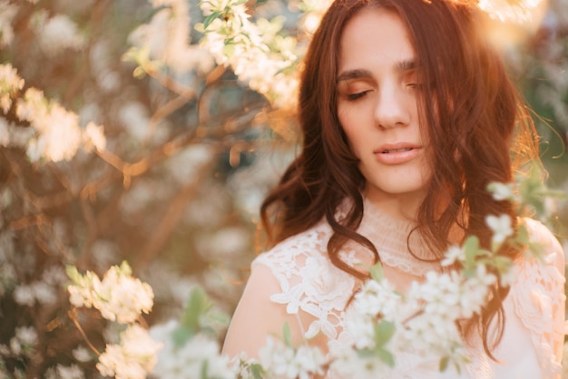 A young girl stands against the background of flowering trees