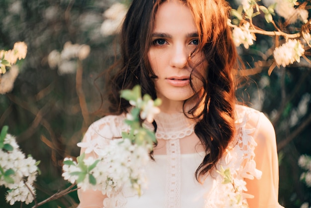 A young girl stands with of flowering trees