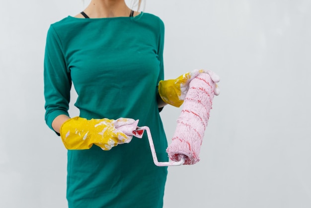 A young girl stands with a pink roller in her hands against a white wall in a new apartment Renovation of the interior and a new apartment Housewarming and a desirable mortgage