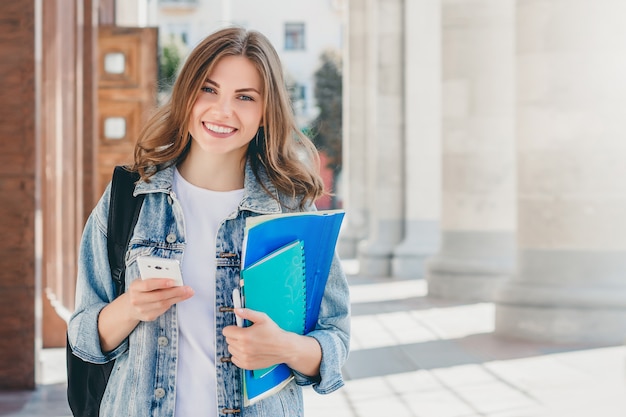 Young girl student smiling against university. 