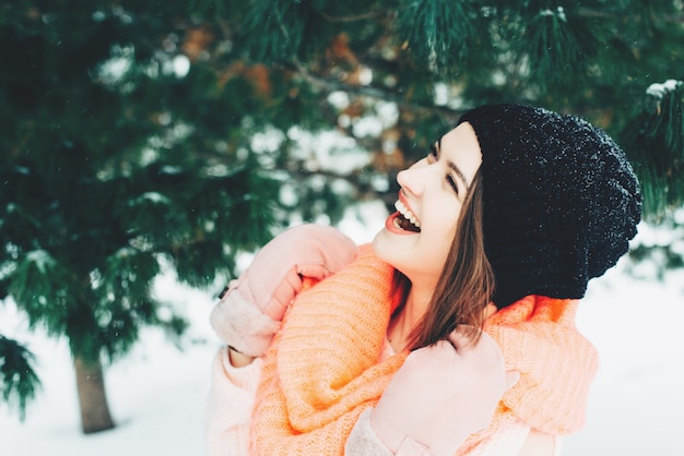 Young girl in a sweater and pink snood enjoys nature outdoors in winter