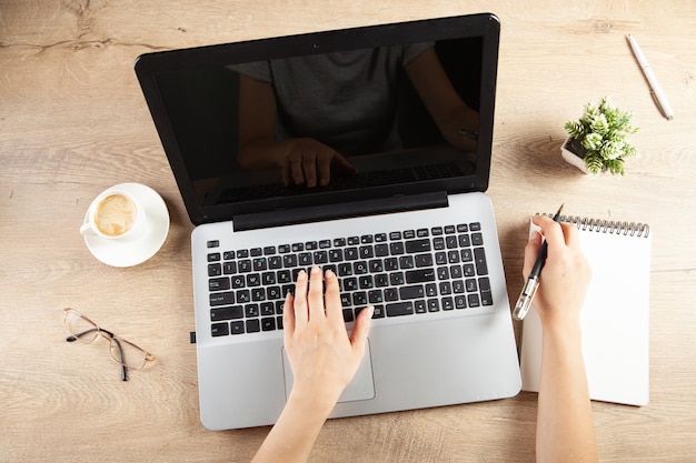 Young girl taking notes in a notebook in front of a work table