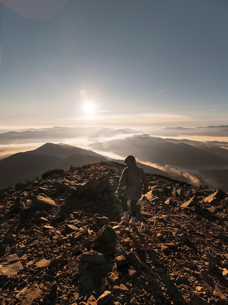 Young girl on top of the mountain in the morning at sunrise. Hiking in mountains.