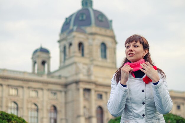 Photo young girl traveler with white jacket straighten red scarf and looking away kunsthistorisches museum