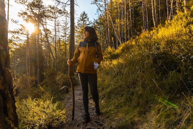 A young girl on a trek through the woods one afternoon at sunset