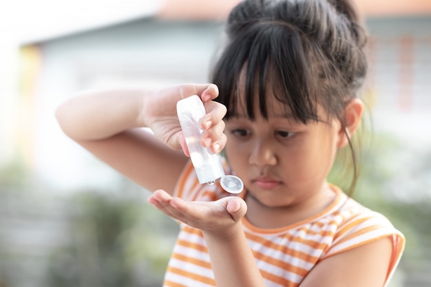 Young girl use alcohol to wash hands