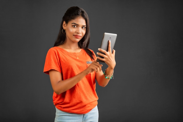 Young girl using mobile phone or smartphone on gray background