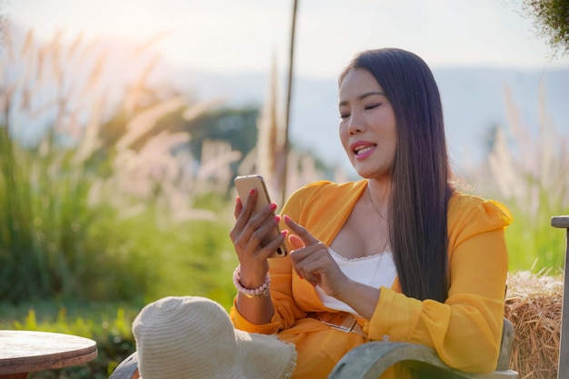 Young girl visits an online dating site via chat on her phone at the flower garden.