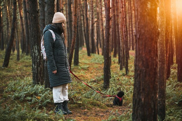 Young girl walking with black cat on a leash in the park