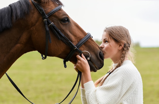 Young girl walking with a horse in nature.