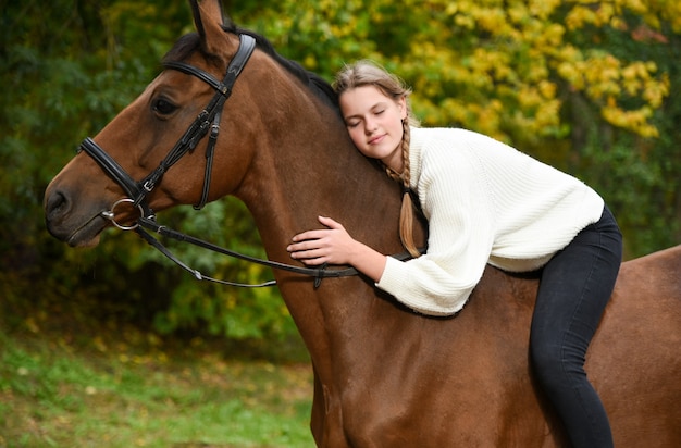 Young girl walking with a horse in nature.