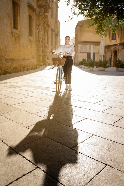 Young girl walks pushing a bicycle on a sunny day in a city break