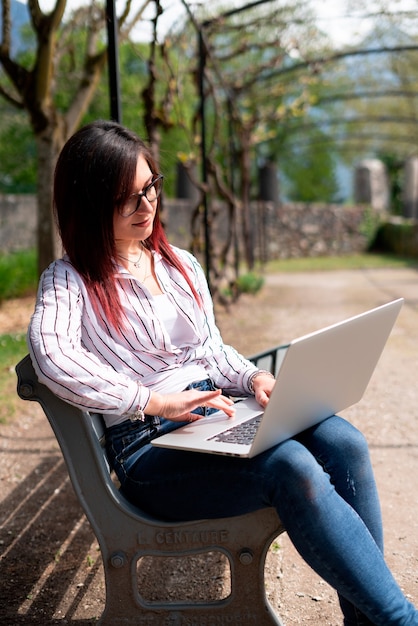 Young girl waring a shirt and looking at laptop in a park