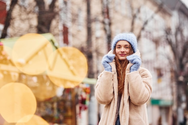 Young girl in warm clothes have a walk outdoors in the city.