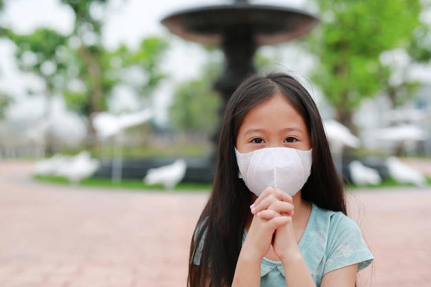 Young girl wear face mask with pray gesture for stop covid19 during coronavirus outbreak