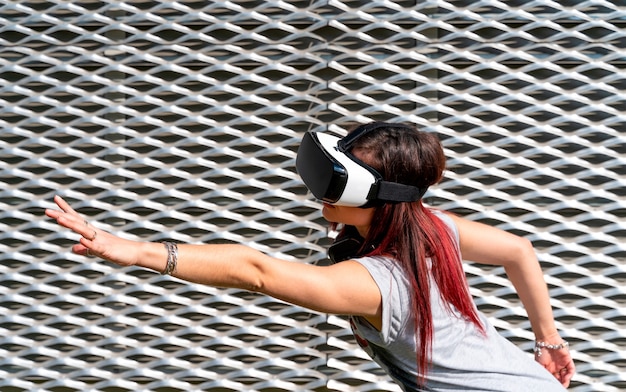 Young girl wearing VR glasses and headphones in a grey background