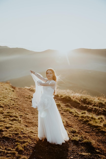 young girl in a wedding dress walk in the mountains at sunrise in the morning