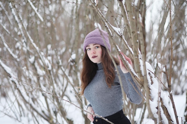 A young girl in a winter park on a walk Christmas holidays in the winter forest The girl enjoys winter in the park