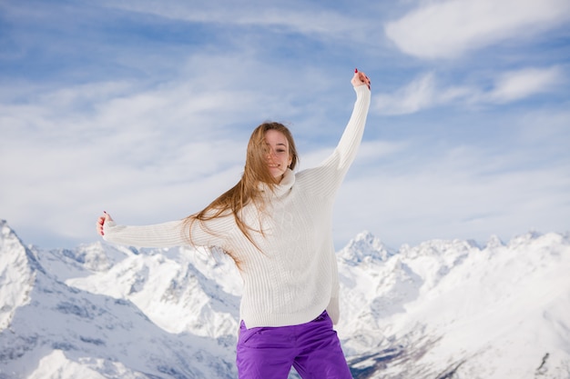 Young girl in a winter suit smiling in the mountains