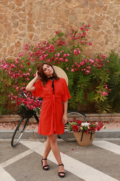 Young girl with a bike.Girl in retro dress with a basket of flowers on the bike.