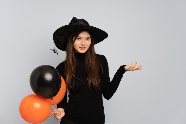 Young girl with black hat and black dress holding ballons