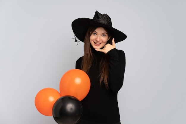 Young girl with black hat and black dress holding ballons