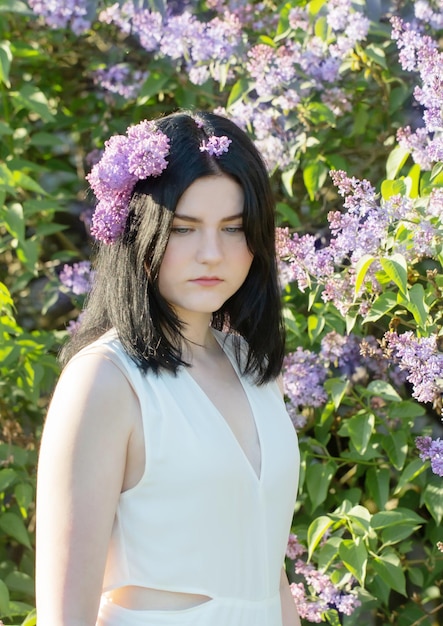 Young girl with blooming lilac in sunlight