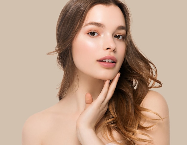 Young girl with care beautiful healthy clean skin and hand touching face. Color background. Brown