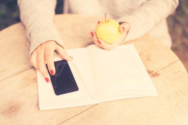 Young girl with cell phone diary and green apple vintage photo effect