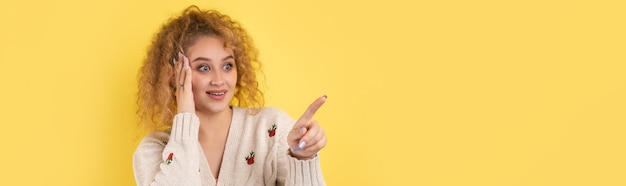 A young girl with curly hair points with a gesture on a studio background